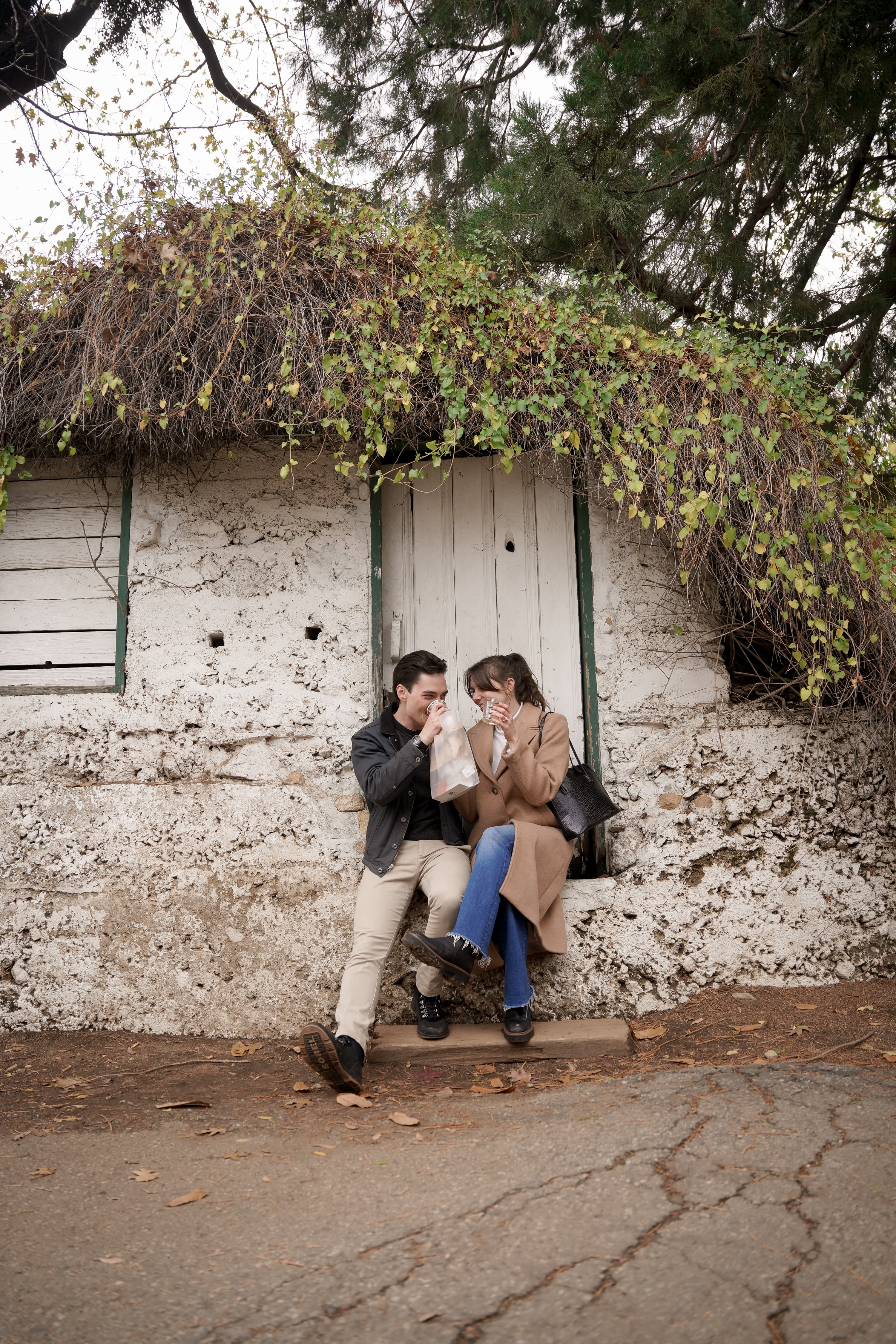 Jax and Jo sharing a toast outside an ivy-covered building