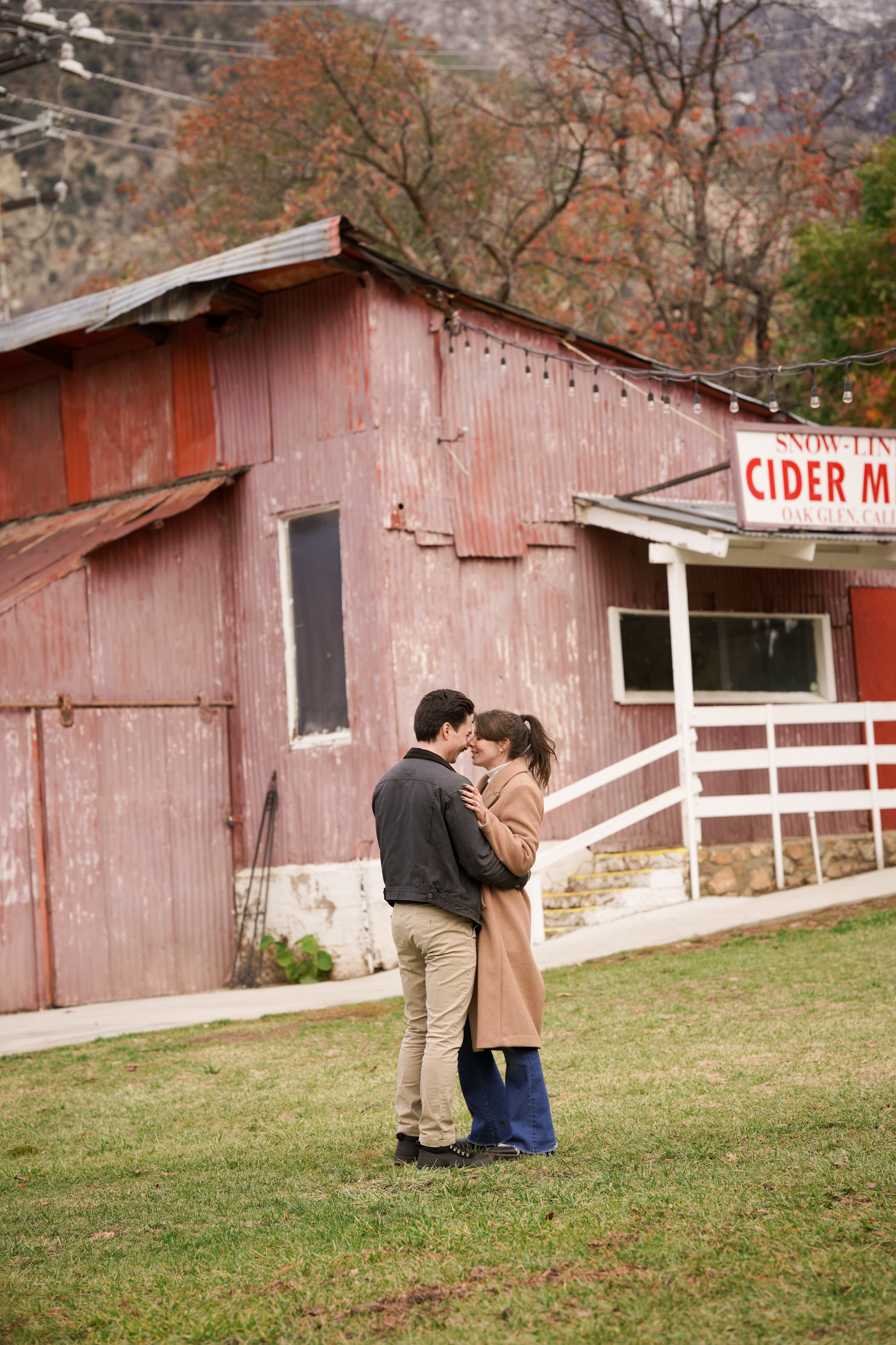 Jax and Jo embracing outside a red cider mill