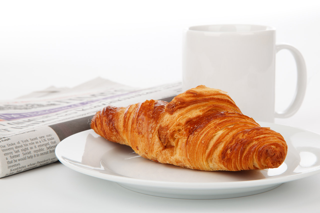 Croissant, tea and a newspaper on a breakfast table